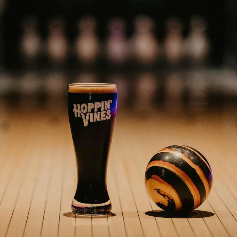A glass of draft stout beer next to a bowling ball